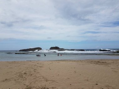 Isabela Porto Riko 'da kumlu plajda insanlar suda.