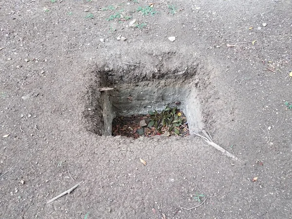square hole in dirt or soil outside