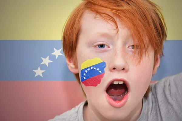 Рудий хлопчик-вентилятор з венесуельським прапором, намальованим на його обличчі — стокове фото