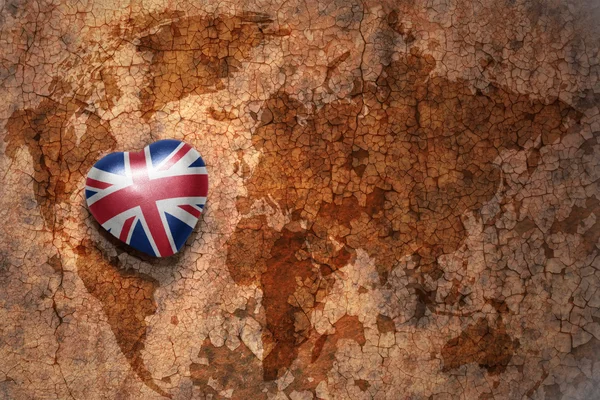 Серце з національним прапором Великої Британії на вінтажній карті світу тріщин паперу фон — стокове фото