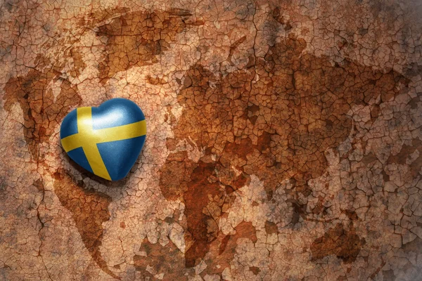 Hjärta med nationella flagga Sverige på en vintage världen karta spricka papper bakgrund — Stockfoto