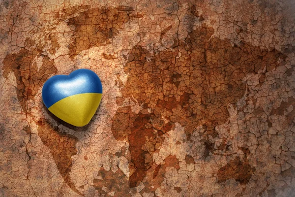 Heart with national flag of ukraine on a vintage world map crack paper background — Stock Photo, Image