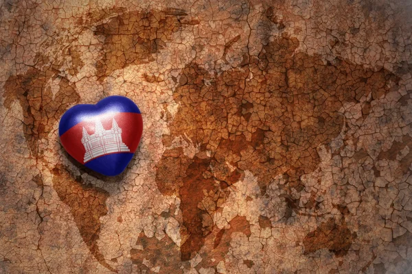 Heart with national flag of cambodia on a vintage world map crack paper background. — Stock Photo, Image