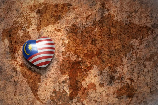 Heart with national flag of malaysia on a vintage world map crack paper background. — Stock Photo, Image