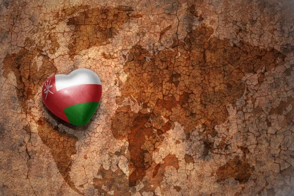 Heart with national flag of oman on a vintage world map crack paper background. — Stock Photo, Image