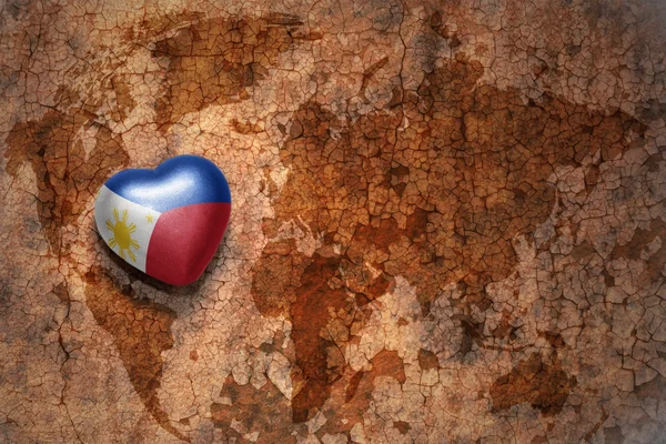 Corazón con la bandera nacional de Filipinas en un fondo de papel crack mapa del mundo vintage . —  Fotos de Stock