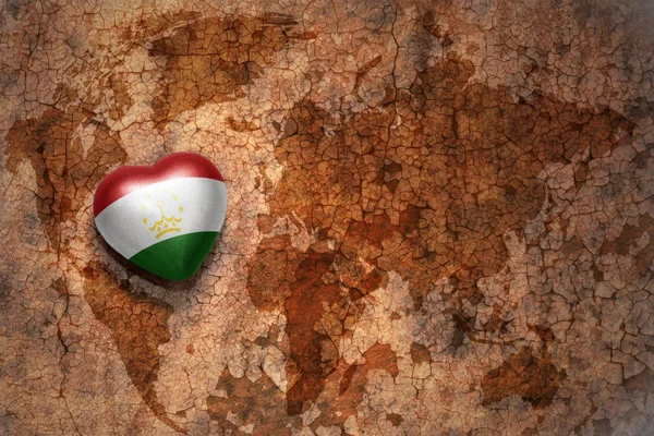 Heart with national flag of tajikistan on a vintage world map crack paper background. — Stock Photo, Image