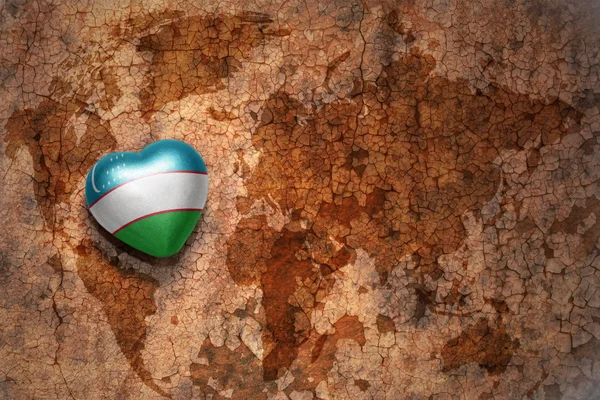 Heart with national flag of uzbekistan on a vintage world map crack paper background. — Stock Photo, Image