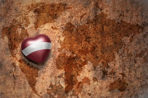 Heart med Lettlands nationella flagga på en Vintage världskarta spricka papper bakgrund. Koncept — Stockfoto