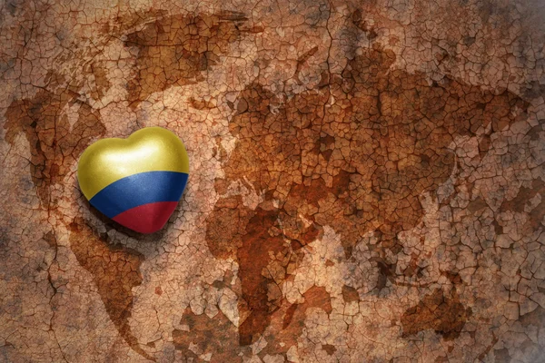 ヴィンテージ世界地図亀裂紙の背景にコロンビアの国旗を持つ心。概念 — ストック写真