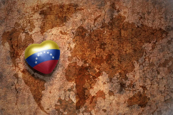 Серце з національним прапором Венесуели на вінтажній карті світу тріщин паперу фону. концепція — стокове фото