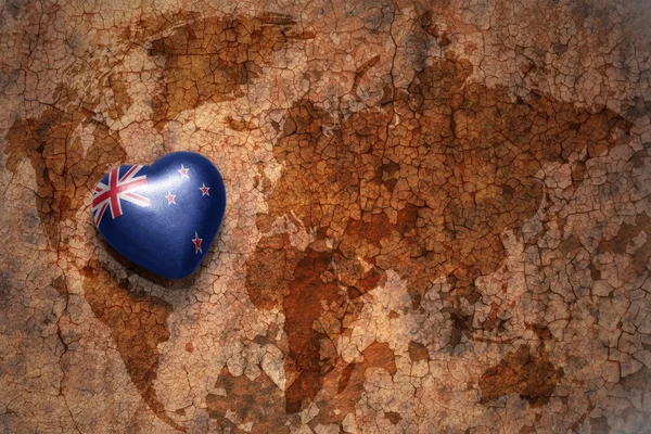 Herz mit Nationalflagge Neuseelands auf einem alten Weltkarten-Risspapier-Hintergrund. — Stockfoto