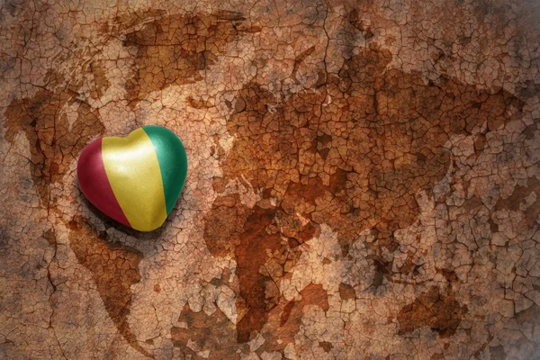 Сердце с национальным флагом Гвинеи на винтажной карте мира крэк бумажный фон . — стоковое фото