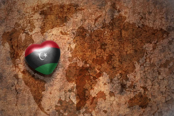 Heart with national flag of libya on a vintage world map crack paper background. — Stock Photo, Image