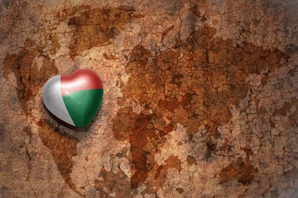 Heart with national flag of madagascar on a vintage world map crack paper background. — Stock Photo, Image