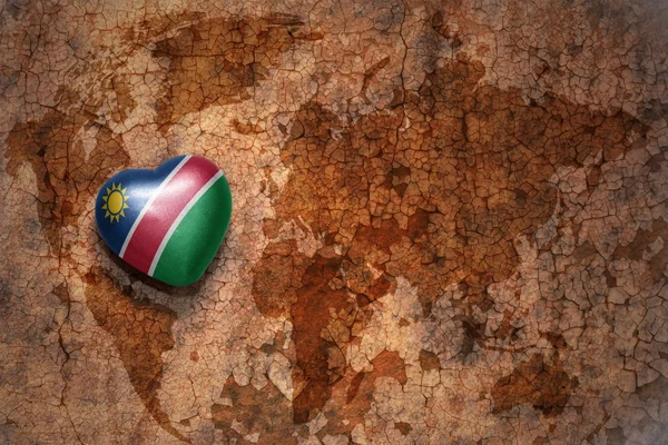 Bir vintage dünya haritası çatlak kağıt arka plan namibya ulusal bayrağı ile kalp. — Stok fotoğraf