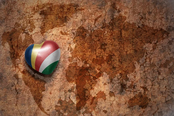 Heart with national flag of seychelles on a vintage world map crack paper background. — Stock Photo, Image