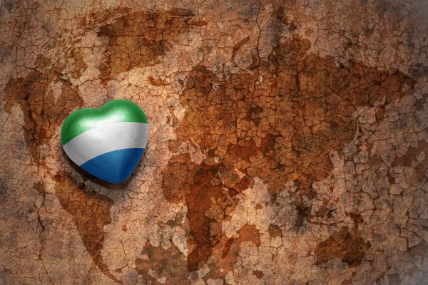 Heart with national flag of sierra leone on a vintage world map crack paper background. — Stock Photo, Image