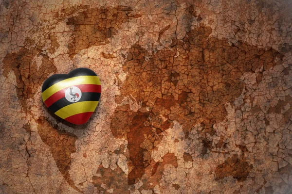 Hjärta med nationella flagga uganda på vintage världen karta spricka papper bakgrund. — Stockfoto