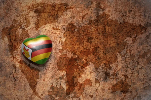 Hjärta med nationella flagga zimbabwe på vintage världen karta spricka papper bakgrund. — Stockfoto