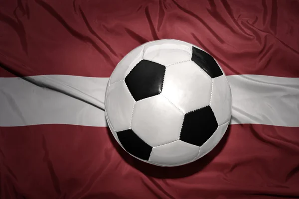 Ballon de football noir et blanc sur le drapeau national de latvia — Photo