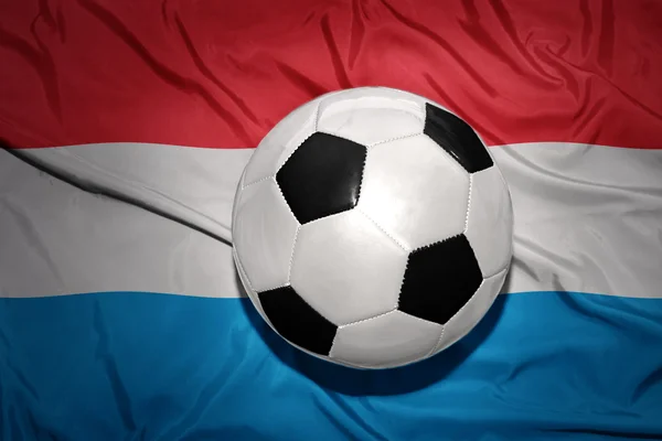 Pelota de fútbol blanco y negro en la bandera nacional de Luxemburgo — Foto de Stock