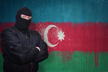 dangerous man in a mask standing near a wall with painted national flag of azerbaijan