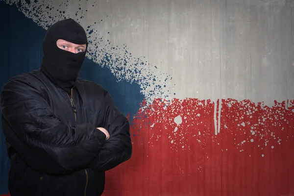 Hombre peligroso en una máscara de pie cerca de una pared con la bandera nacional pintada de la República Checa — Foto de Stock