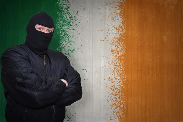 アイルランドの国旗を描いた壁の近くに立つマスクの危険な男 — ストック写真