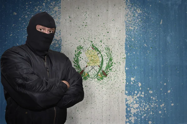 Homem perigoso em uma máscara que está perto de uma parede com a bandeira nacional pintada de guatemala — Fotografia de Stock