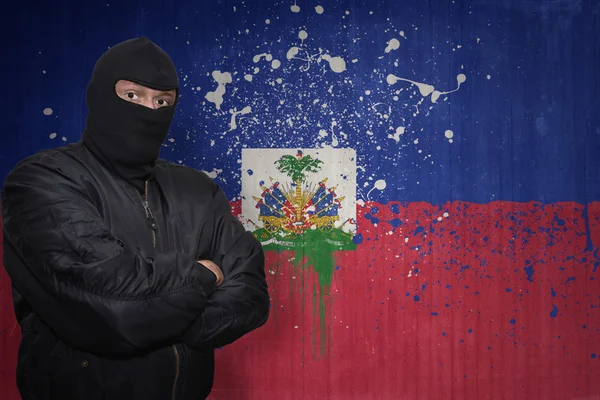 Veszélyes ember a maszk közelében álló fal festett nemzeti zászló Haiti — Stock Fotó