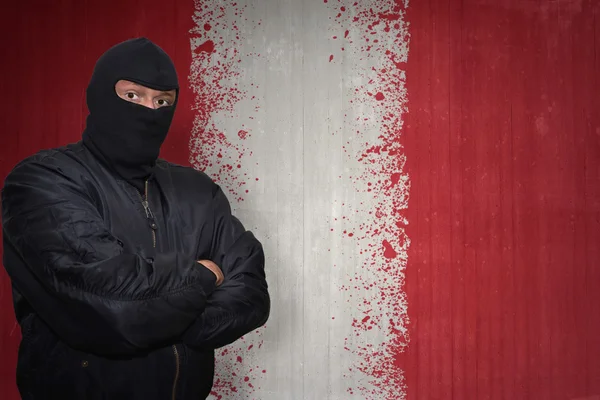 Dangerous man in a mask standing near a wall with painted national flag of peru — Stock fotografie