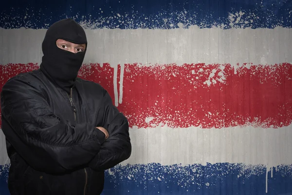 Farlig man i en mask stående nära en mur med målade nationella flaggan i Costa Rica — Stockfoto