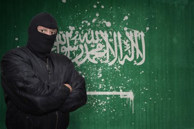 bir maske daimi bir duvar boyalı Suudi Arabistan bayrağı ile yakın tehlikeli adam