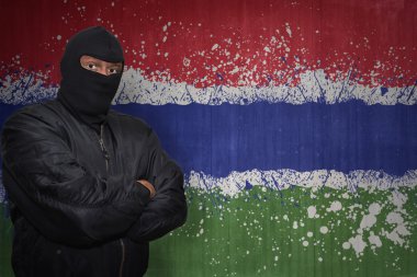 Gambiya boyalı ulusal bayrak bir duvarla yakınındaki bir maske ayakta tehlikeli adam