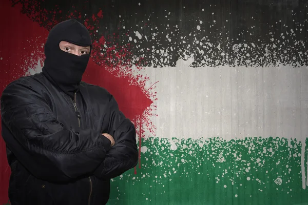 Om periculos într-o mască stând lângă un zid cu steagul național pictat al lui Iordan — Fotografie, imagine de stoc