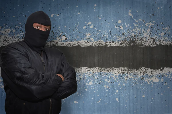 Dangerous man in a mask standing near a wall with painted national flag of botswana — Stock Photo, Image