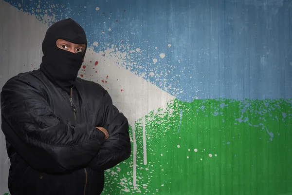 Homem perigoso em uma máscara que está perto de uma parede com a bandeira nacional pintada de djibuti — Fotografia de Stock