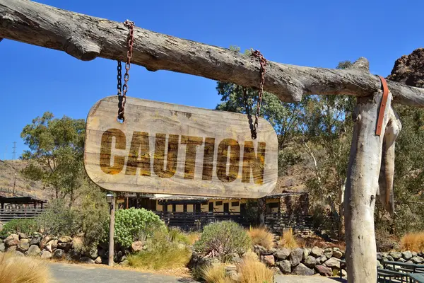 Old wood signboard with text "caution " hanging on a branch — Stock Photo, Image