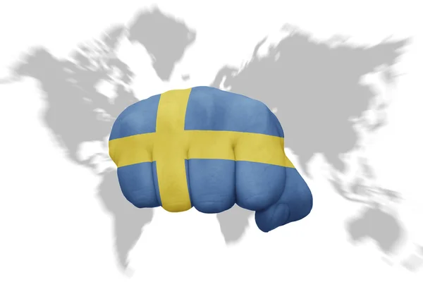 Faust mit der schwedischen Nationalflagge auf einem Weltkartenhintergrund — Stockfoto