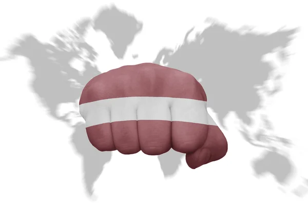 Fist with the national flag of latvia on a world map background — Stock Photo, Image