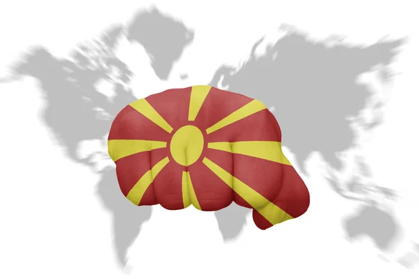 Pěst s národní vlajka Makedonie na pozadí mapy světa — Stock fotografie