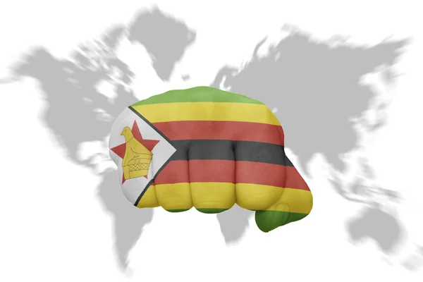 Punho com a bandeira nacional de zimbabwe em um fundo de mapa do mundo — Fotografia de Stock