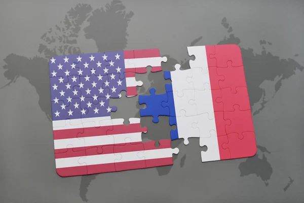 Puzzle avec le drapeau national des États-Unis d'Amérique et de la France sur un fond de carte du monde — Photo