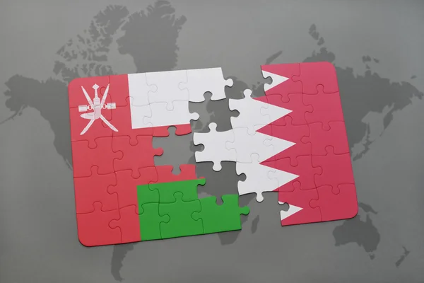 Rompecabezas con la bandera nacional de Omán y Bahréin en un mapa del mundo de fondo . — Foto de Stock