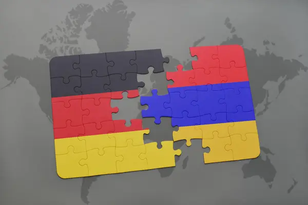 Puzzle avec le drapeau national de l'Allemagne et l'arménie sur un fond de carte du monde . — Photo