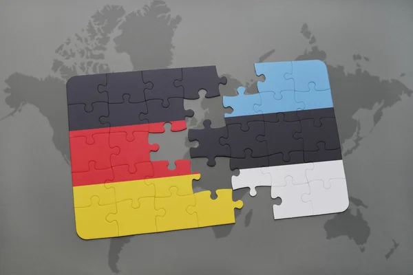 Rompecabezas con la bandera nacional de Alemania y Estonia en un mapa del mundo de fondo . — Foto de Stock