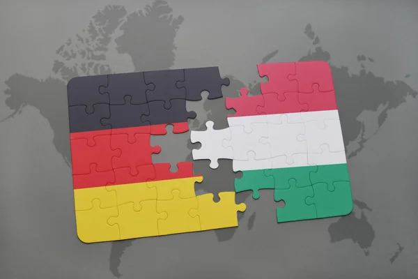 Puzzle avec le drapeau national de l'Allemagne et la Hongrie sur un fond de carte du monde . — Photo
