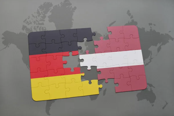 Quebra-cabeça com a bandeira nacional da alemanha e latvia em um fundo de mapa do mundo . — Fotografia de Stock