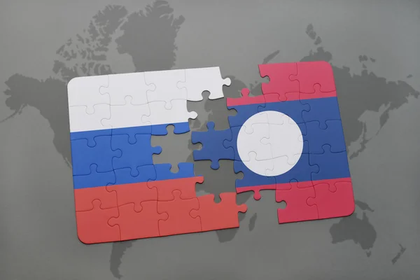 Puzzel met de nationale vlag van Rusland en Laos op een wereld kaart achtergrond. — Stockfoto